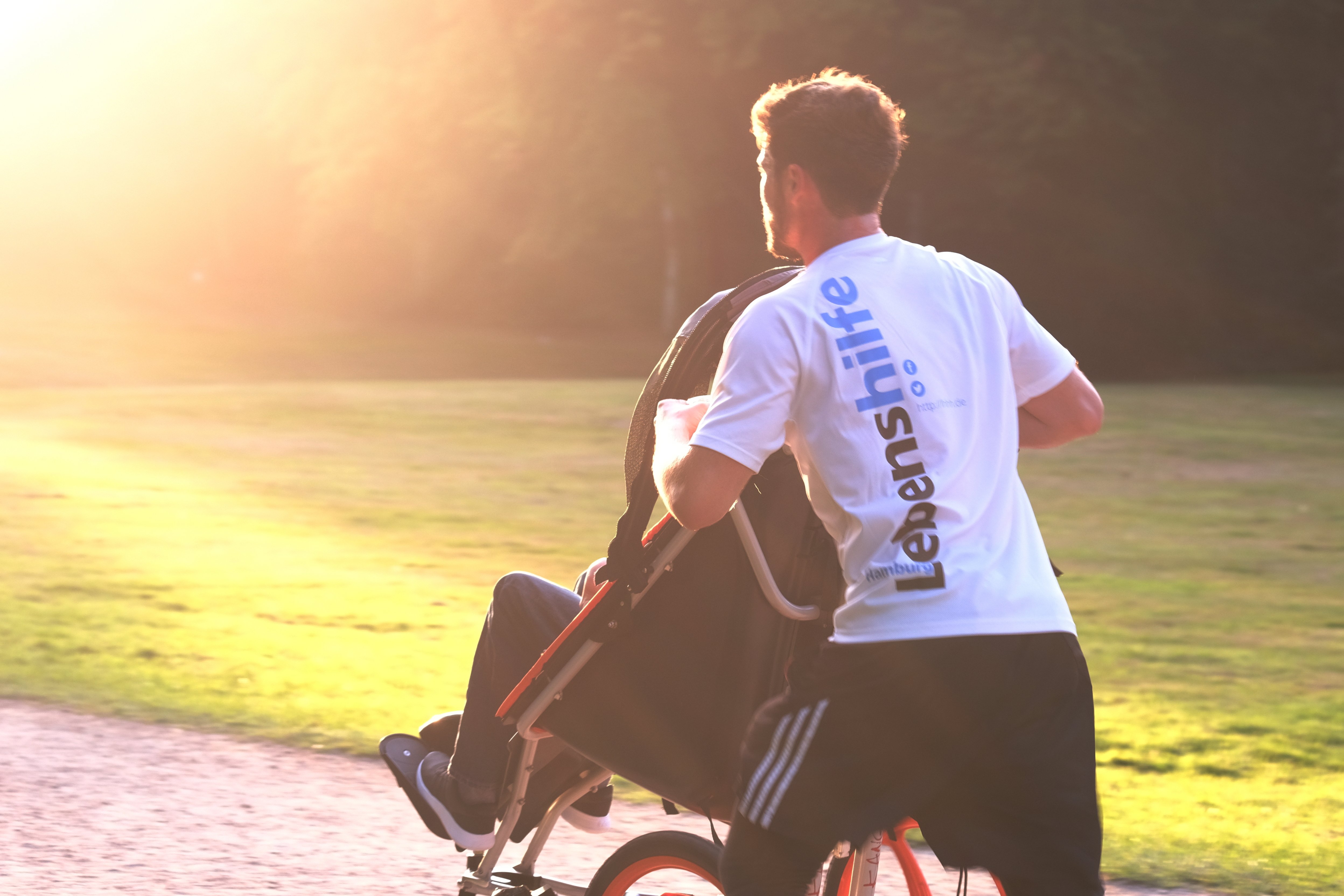Ein Mann joggt und schiebt dabei eine Person im Rollstuhl an