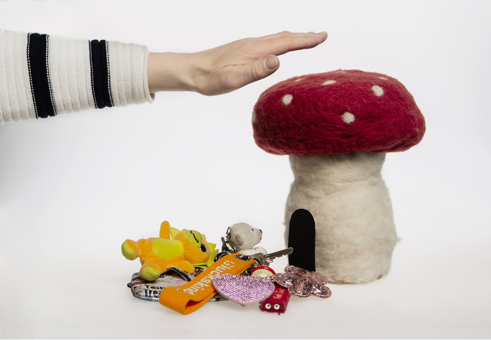 jemand hält die Hand über einen Pilz aus Filz, darunter liegt ein Schlüsselbund