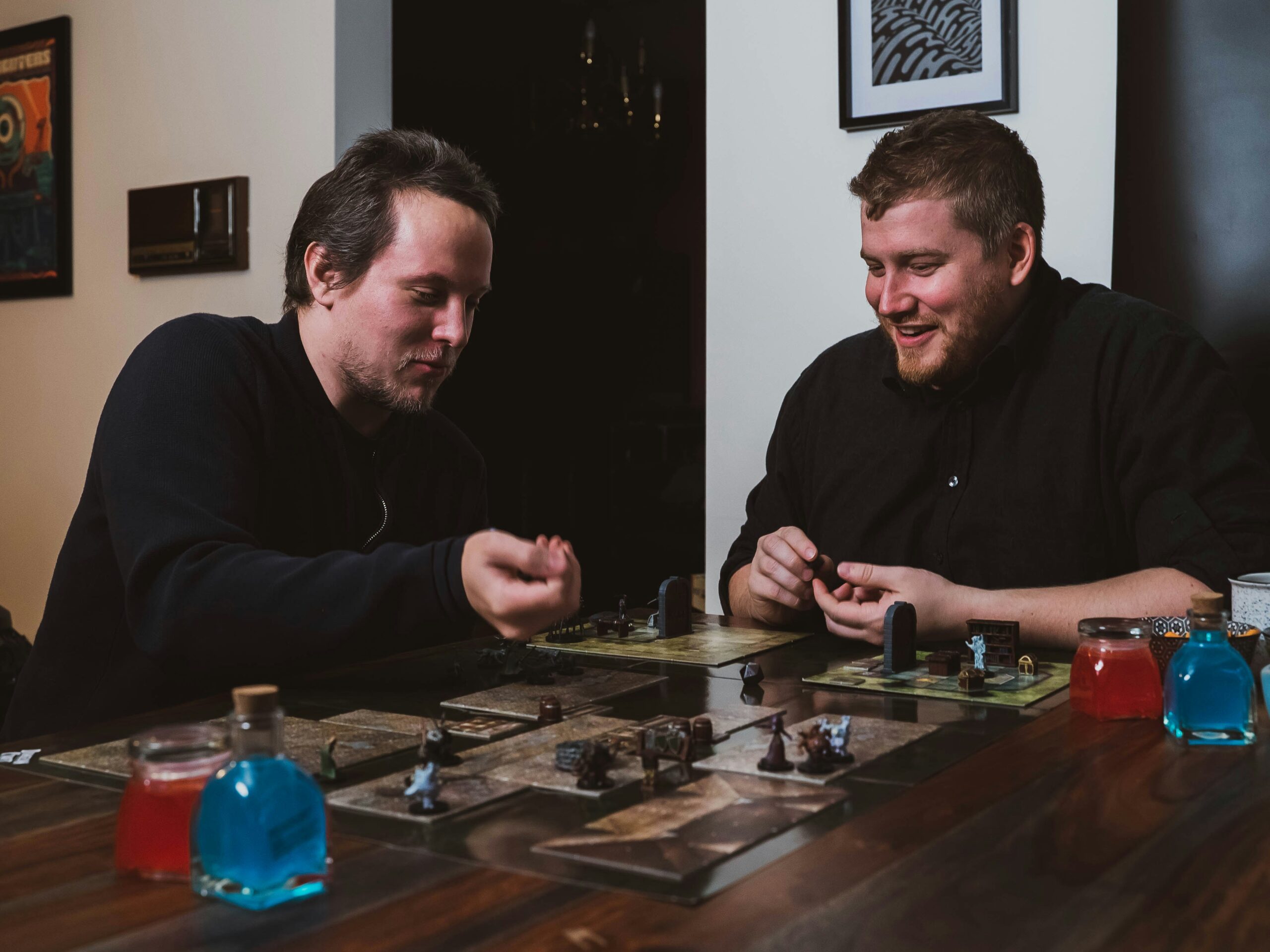 Zwei junge Männer sitzen am Tisch und spielen ein Brettspiel.